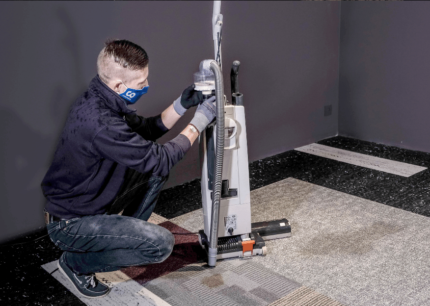 Professionnel de l'entretien de moquette travaillant pour Composil à l'aide d'une shampouineuse